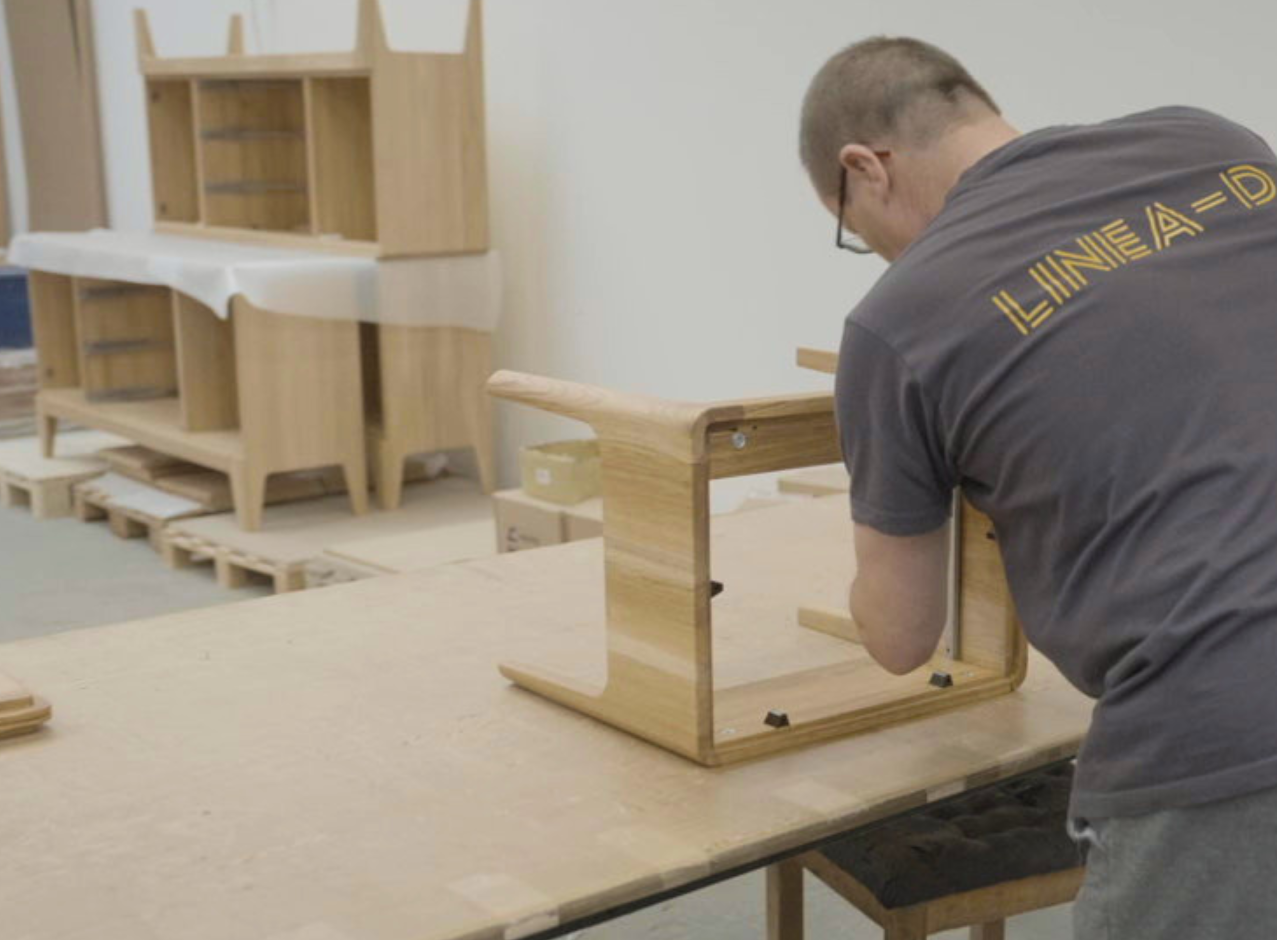 A Linea-D employee assembling a solid wood bedside table