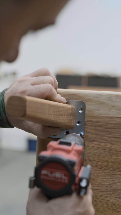 A Linea-D employee fastening solid wood table legs by hand